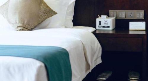 a bedroom with a bed and a night stand with a clock at Manhatton Hotel Beihai in Beihai