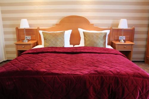a bedroom with a large bed with a red comforter at Hotel Wegner - T h e culinary art hotel in Hannover