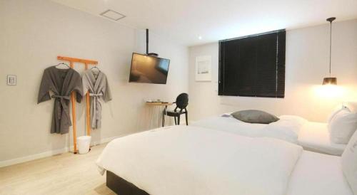 a bedroom with a large white bed and a tv at Hotel Yam ANDONG in Andong