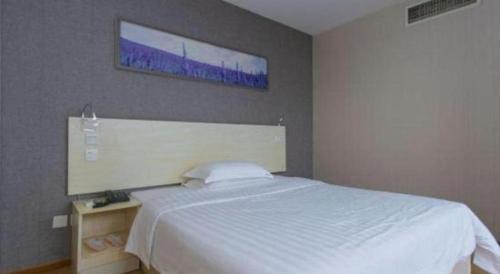 a bedroom with a white bed and a painting on the wall at 7 Days Inn Chengdu Huayang Metro Station Binfen Plaza in Chengdu