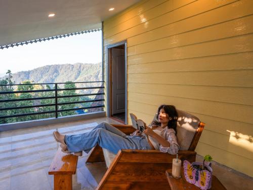 eine Frau auf einem Stuhl auf einem Balkon in der Unterkunft Moustache Select Mukteshwar in Mukteswar