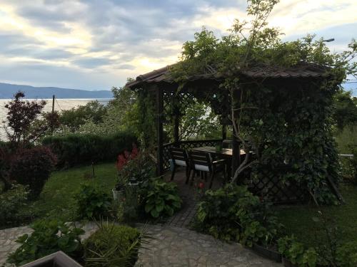 a table and bench under a gazebo in a garden at Villa Pavlina in Ohrid