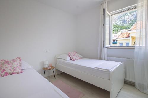a white room with two beds and a window at Apartments Villa Flamingo in Makarska