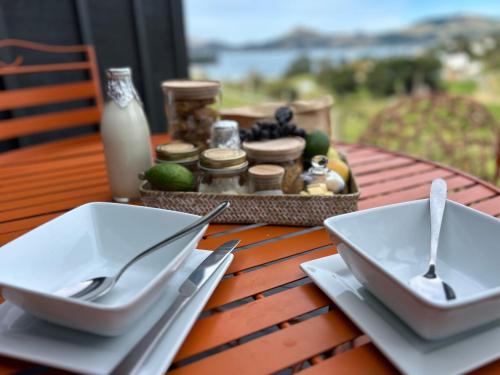 a table with two white plates and silverware on it at Harbour Hideaway in Dunedin