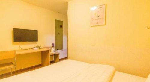 a room with a bed and a desk with a television at 7 Days Inn Hohhot University East Street in Hohhot