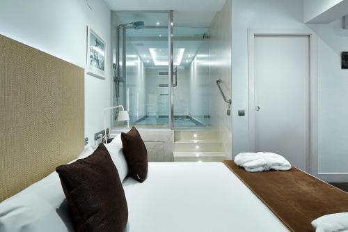 a bedroom with a large bed and a shower at Gaudint Barcelona Suites in Barcelona