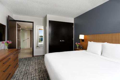 a bedroom with a large white bed and a bathroom at Hyatt Place Manati in Manati