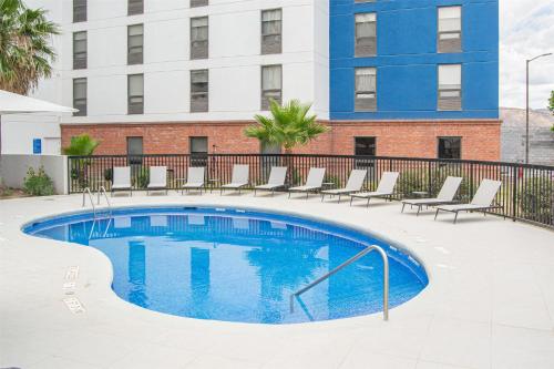 a swimming pool with chairs and a building at Hampton by Hilton Saltillo Zona Aeropuerto in Saltillo