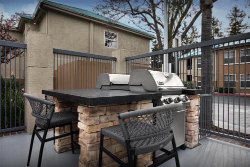 a grill and two chairs on a patio with a fence at Homewood Suites by Hilton San Jose Airport-Silicon Valley in San Jose