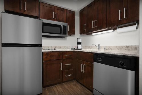 a kitchen with a white refrigerator and wooden cabinets at Homewood Suites by Hilton San Jose Airport-Silicon Valley in San Jose