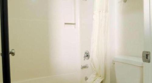 a white bathroom with a tub and a shower curtain at Best Western Hanford Inn in Hanford