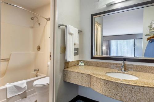 a bathroom with a sink and a toilet and a mirror at Quality Inn Mount Airy Mayberry in Mount Airy