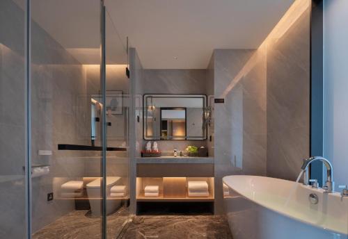 un bagno con vasca, lavandino e specchio di Howard Johnson Airport Hotel Changsha a Changsha