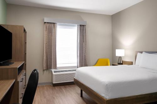 a hotel room with a bed and a window at ECHO Suites Extended Stay by Wyndham Indianapolis AmeriPlex in Indianapolis