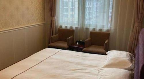 a bedroom with two chairs and a bed and a window at Yiwu Baiheng Hotel in Yiwu
