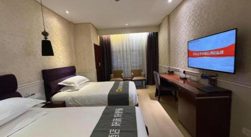 a hotel room with two beds and a desk and a flat screen tv at Yiwu Baiheng Hotel in Yiwu