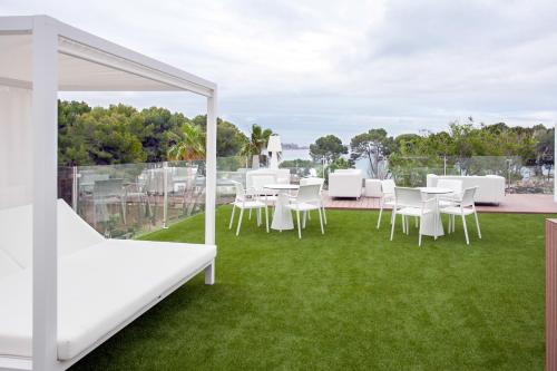 a patio with white chairs and tables on the grass at Morlans Garden in Paguera