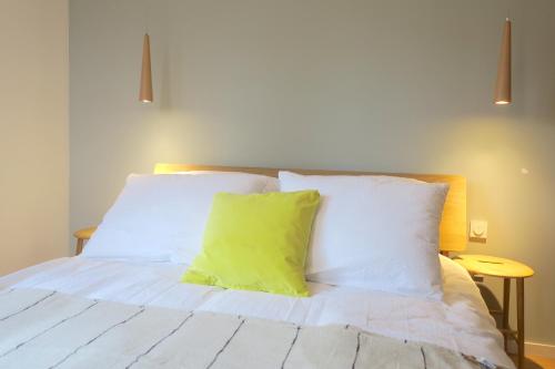 a white bed with a green pillow on it at Versant de vigne in Chalon-sur-Saône