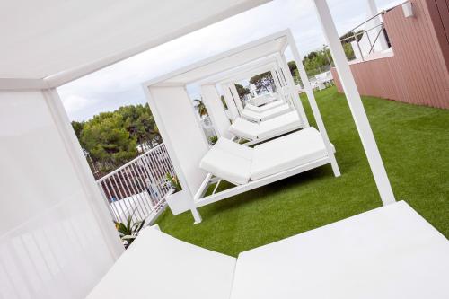 a porch with two white chairs on a lawn at Morlans Garden in Paguera