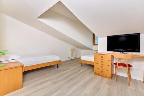 a bedroom with a bed and a desk with a tv at Hotel Geier in Nago-Torbole