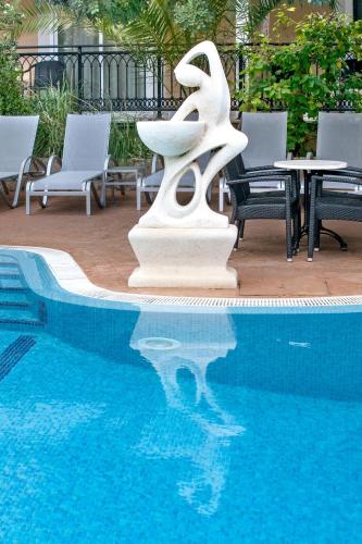 a white sculpture next to a pool with chairs and tables at Morlans Garden in Paguera