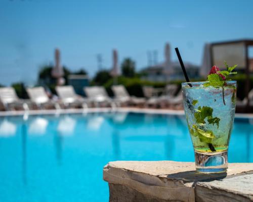 a drink sitting on a ledge next to a swimming pool at Dennys Inn Hotel in Kalamaki