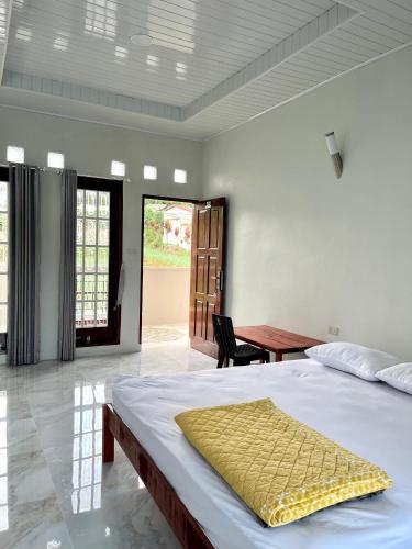 a bedroom with a bed with a yellow blanket on it at Caesarea Guesthouse in Berastagi