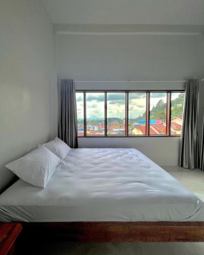 a bed in a bedroom with a large window at Caesarea Guesthouse in Berastagi