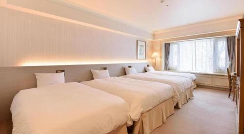 two beds in a room with a window at Hotel de Premiere Minowa in Inawashiro