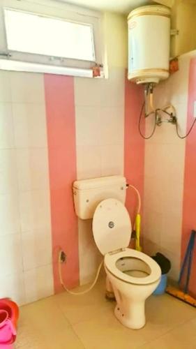 a bathroom with a toilet and a window at Chand Guest house in Kasol