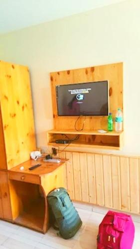 a room with a desk and a television and luggage at Chand Guest house in Kasol