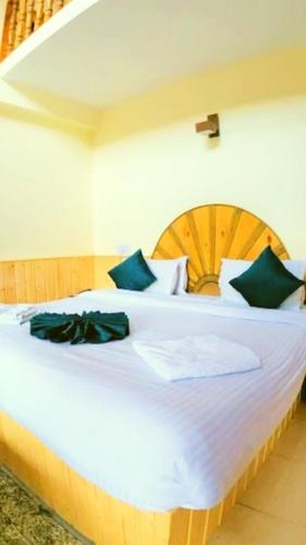 a bedroom with a large white bed with green pillows at Chand Guest house in Kasol