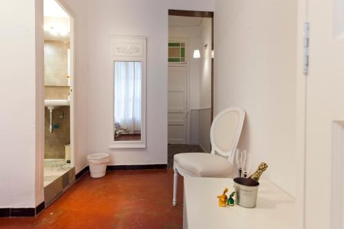 a bathroom with a white chair and a mirror at Hostal Dragonflybcn in Barcelona