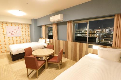 a hotel room with two beds and a table and a window at Hiyori Hotel Osaka Suminoekoen Station in Osaka