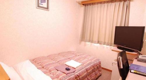 a hotel room with a bed and a television at Chino Station Hotel in Chino