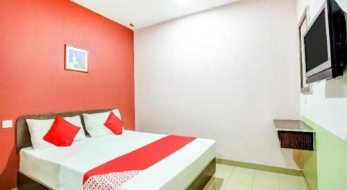 a red room with a bed and a tv at OYO 89539 Hotel Siswa in Kampar