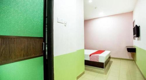 a room with a bed and a green wall at OYO 89539 Hotel Siswa in Kampar