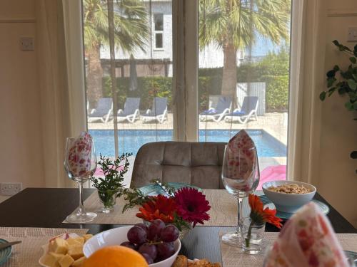 a table with wine glasses and a bowl of food at Villa Eden Palms, Coral-Bay, Pool in Peyia