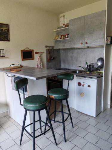 une cuisine avec un comptoir et quatre tabourets de bar verts dans l'établissement Calme et vue magnifique, à Barcelonnette