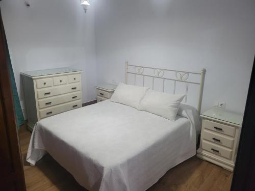 a bedroom with a white bed and two night stands at Chalet rural a las afueras de Montellano in Montellano