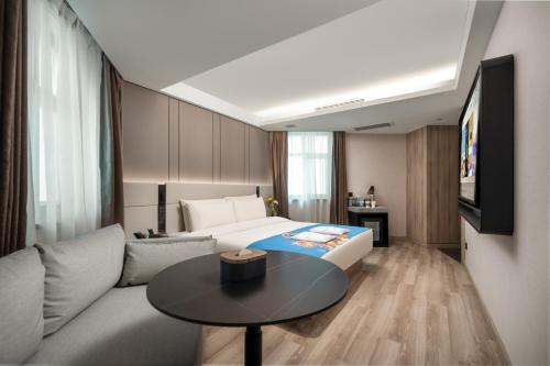 a hotel room with a bed and a table at Atour Hotel Qingdao Olympic Sailing Center May Fourth Square in Qingdao
