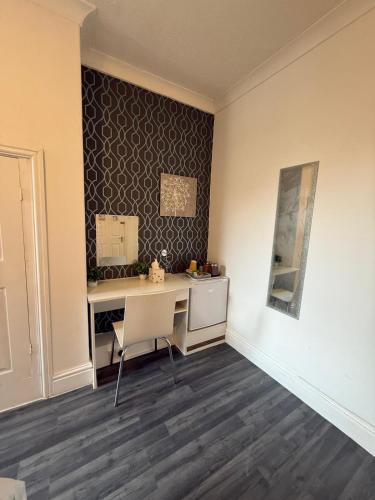 a room with a desk with a chair and a wall at Daville Hotel Blackpool in Blackpool