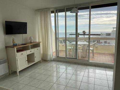 d'un salon avec une télévision et une table ainsi que d'un balcon. dans l'établissement Studio Héliopolis C 36 - 4 personnes, au Cap d'Agde