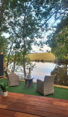 two chairs and a table on a deck next to a lake at The Hide Away Cabin by Tiny Away in Redwoods Valley