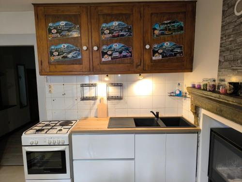 eine Küche mit einer Spüle, einem Herd und Schränken in der Unterkunft Maison de village in La Motte-en-Beauges