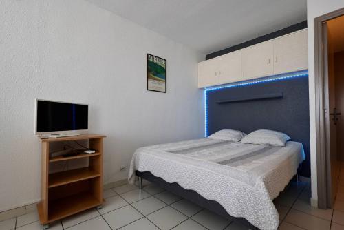 une petite chambre avec un lit et une télévision dans l'établissement Studio Héliopolis D 51 - 4 personnes, au Cap d'Agde