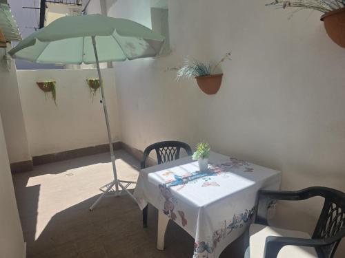 a table with a green umbrella and a table and chairs at La Casa di Maty in Reggio Calabria