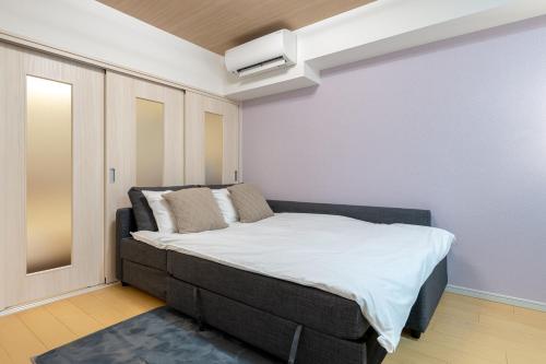a small bedroom with a bed with white sheets at 幡ヶ谷2丁目 in Tokyo