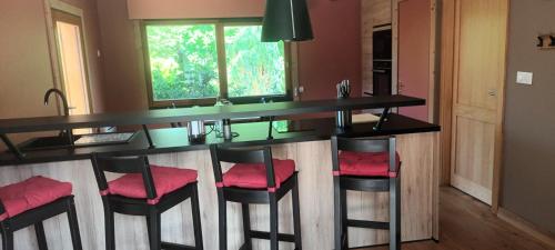 une cuisine avec un bar avec des tabourets rembourrés rouges dans l'établissement G mi cabaña, à La Celle-sous-Gouzon