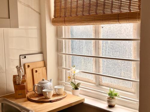 a kitchen counter with a window with cups on it at Candy Cafe Apartment in London